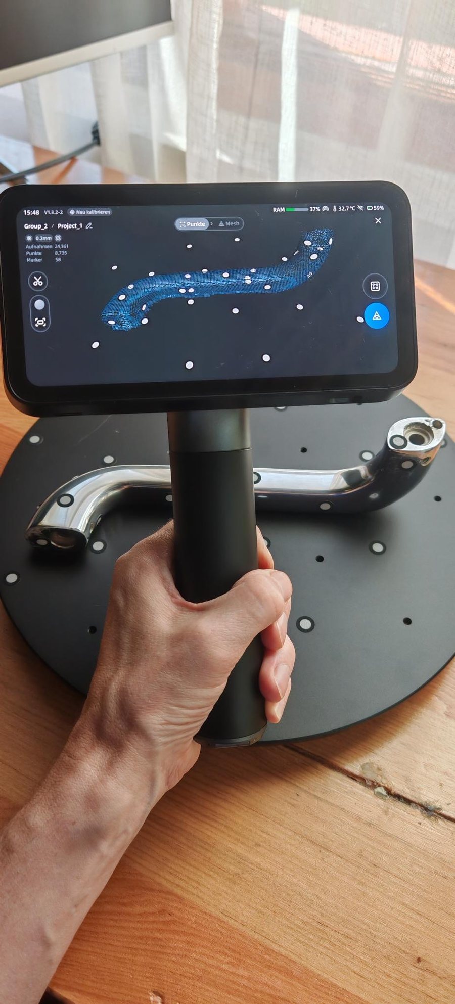 Our handheld 3D scanner over the chrome handle on a turntable dotted with markers, the scan building up on its screen
